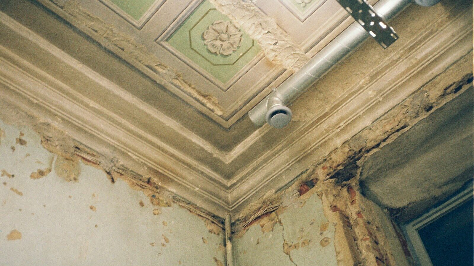 the ceiling of a run down room with peeling paint